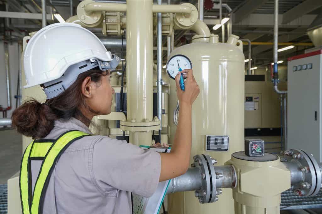 A female engineer in hard hat and high vis inspecting a boiler