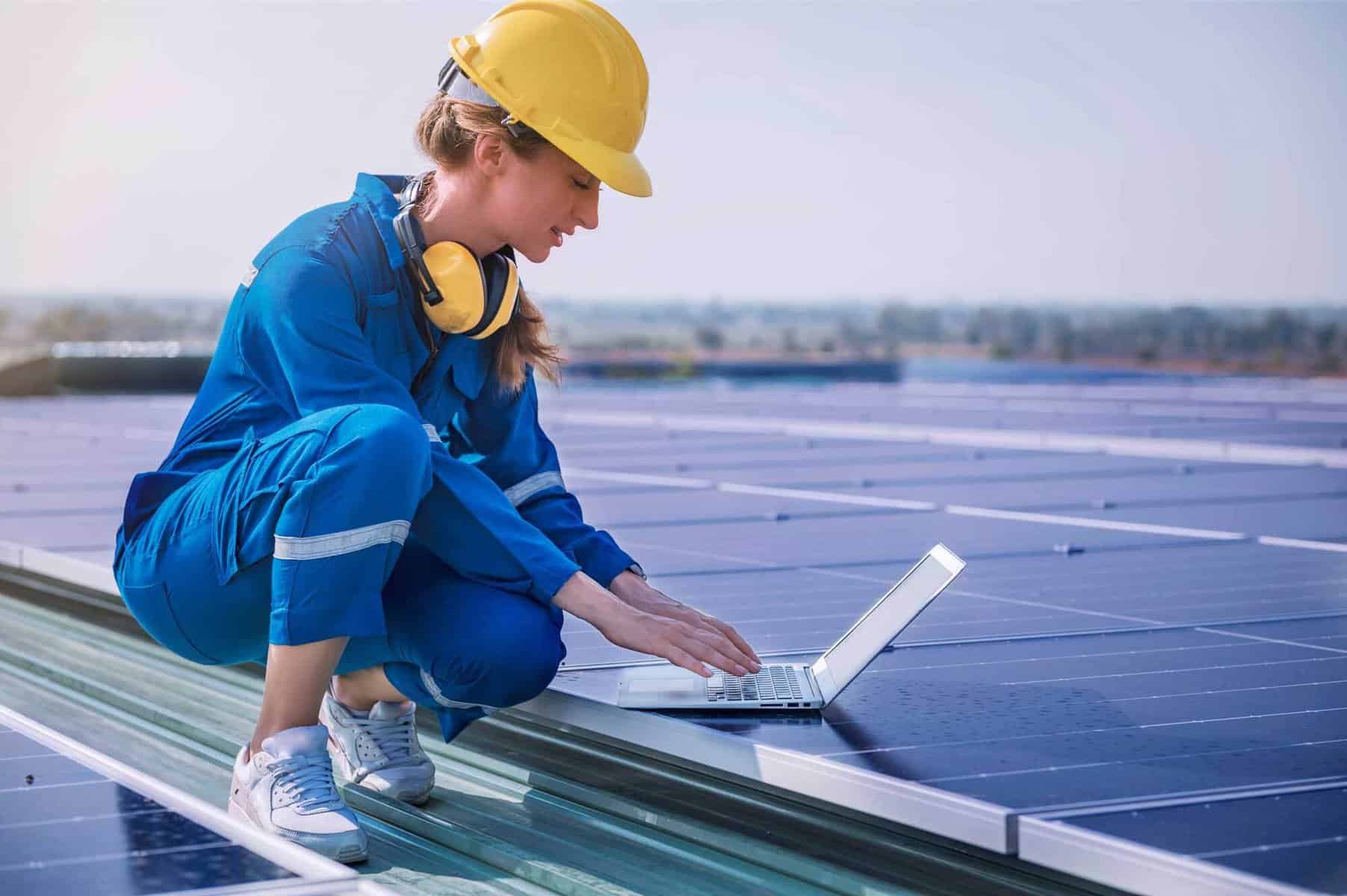 A female engineering with a laptop next to solar panels