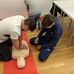 Students practicing CPR on a dummy in a classroom