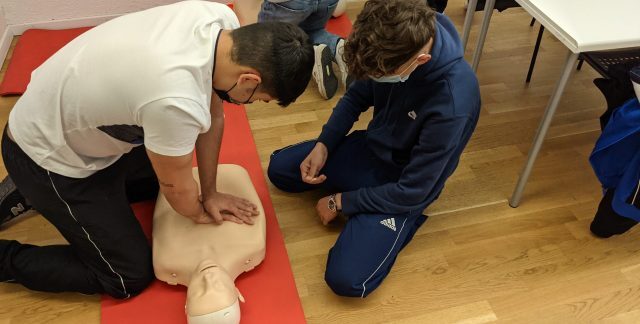 Students practicing CPR on a dummy in a classroom